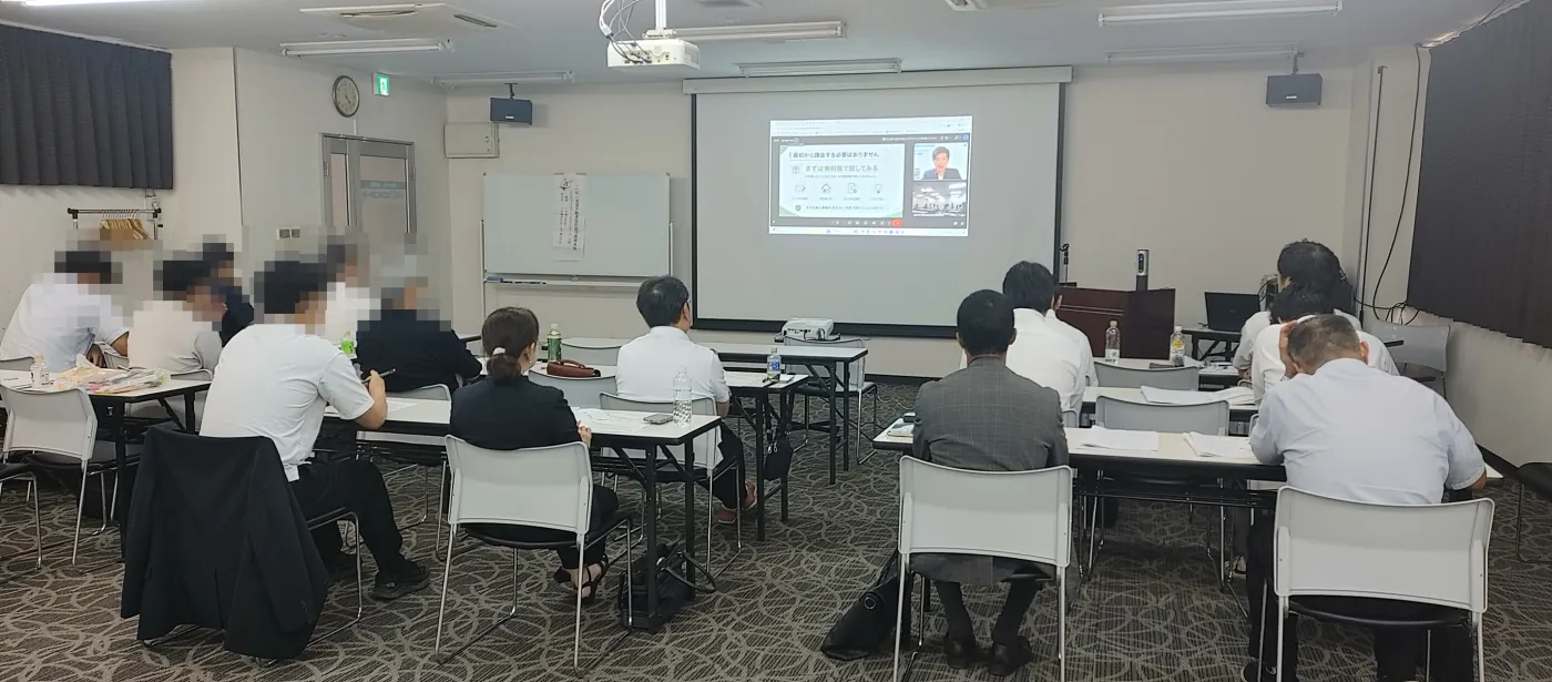 会場後方から見た受講者のみなさま。机の上に資料を広げて画面を見ている